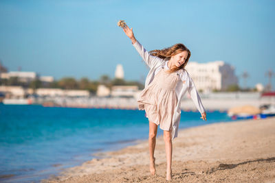 Woman with umbrella on beach against sky