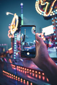 Midsection of man photographing illuminated mobile phone at night