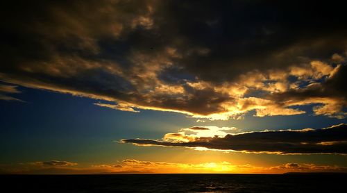 Scenic view of sea against dramatic sky during sunset