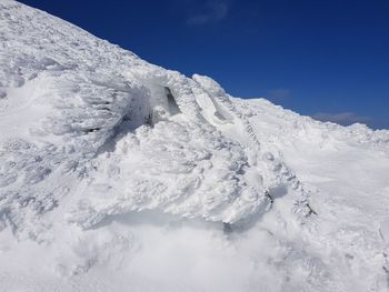 Scenic view of snow mountains against blue sky