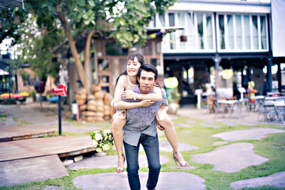 Man piggybacking woman outdoors