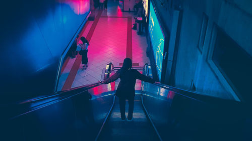 Rear view of woman walking on illuminated stage