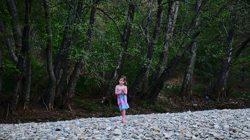 Girl walking on rocks against trees