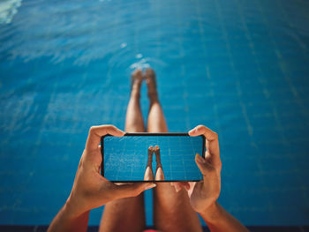 Low section of woman using mobile phone in swimming pool
