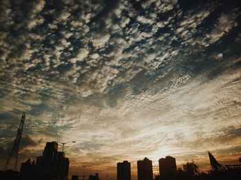 Low angle view of silhouette buildings against dramatic sky