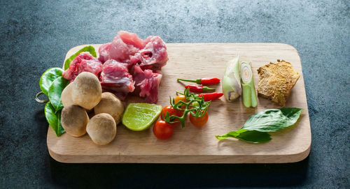 Tomatoes and meat on cutting board over table