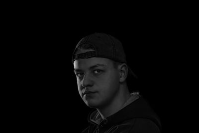 Portrait of young man against black background