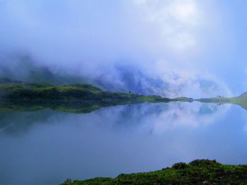 Scenic view of distant cottage in mountains and lake