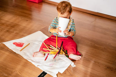 High angle view of girl sitting on hardwood floor at home