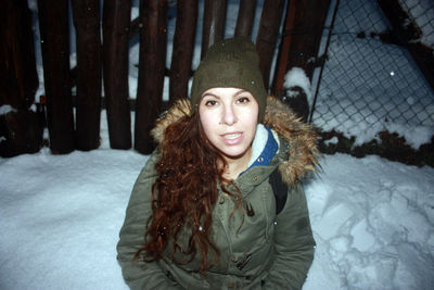 Portrait of smiling young woman in snow during winter