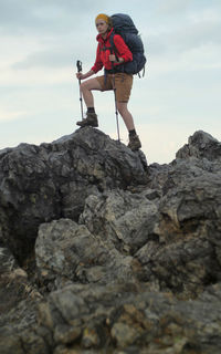 Low angle view of woman on rock against sky