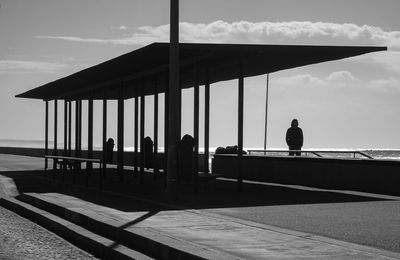 Silhouette people standing by sea against sky
