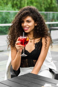 Portrait of a smiling young woman drinking glass