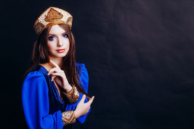 Portrait of beautiful woman in traditional clothing against black background