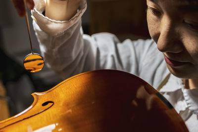 Young chinese violin maker at work in her workshop