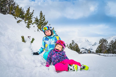 Family, mother and daughter, build a small snowman. ski winter holidays in andorra