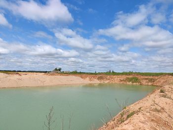 Scenic view of river against cloudy sky