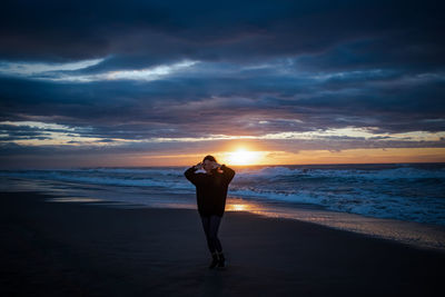 Full length of woman walking on beach during sunset