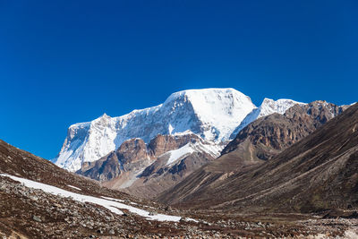 Scenic view of snow covered mountains against clear blue sky