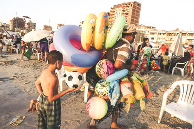 People at beach against sky in city