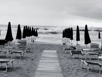 Chairs on beach by sea against sky