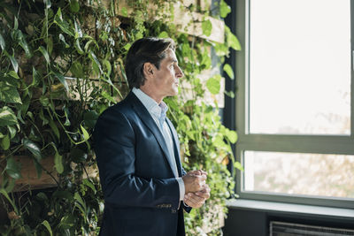 Businessman in green office looking out of window