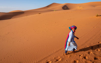 Full length of man on sand dune in desert against sky