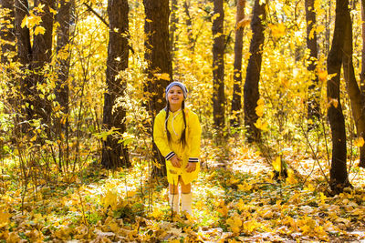 Portrait of smiling young woman in forest during autumn