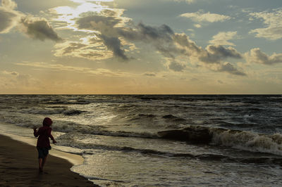 Woman on beach against sky during sunset