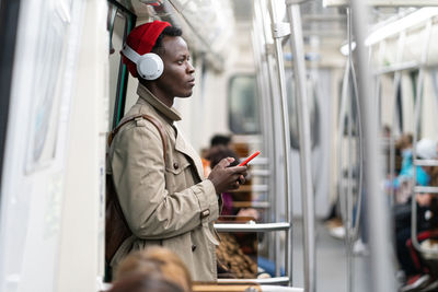 Side view of man using mobile phone in train