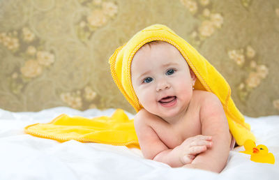 Portrait of happy baby girl lying with towel on head at home