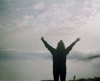 Rear view of silhouette person standing in water against sky