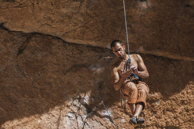 Climber hanging on rope on rough cliff