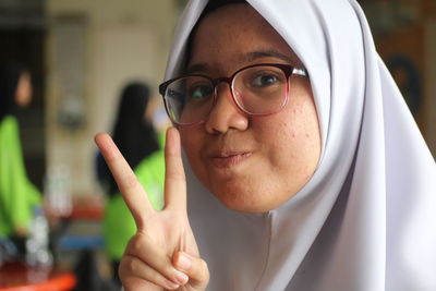 Close-up portrait of mid adult woman showing peace sign