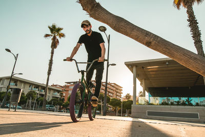 Full length of man riding bicycle on road in city