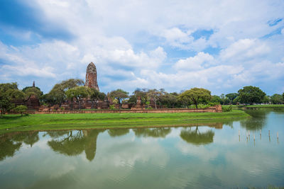 Reflection of temple in lake against cloudy sky