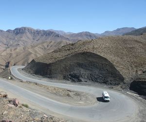 Scenic view of road by mountains against clear sky