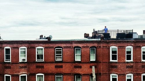 Bird perching on building against sky