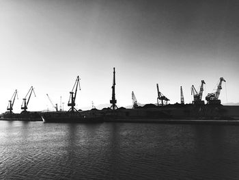 Cranes at commercial dock against clear sky