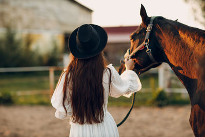 Rear view of woman with horse on field