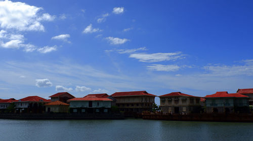 Residential buildings by lake against sky