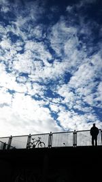 Low angle view of railing against cloudy sky