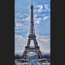 Low angle view of communications tower against cloudy sky