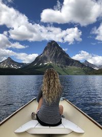 Rear view of woman sitting on boat over lake against sky
