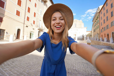 Smiling girl in blue dress and hat takes selfie picture in ancona, marche, italy