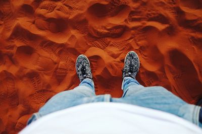 Low section of man standing on sand