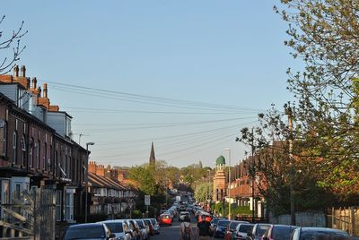 Cars on road by buildings against sky