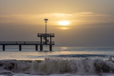 Pier over sea against sky during sunset