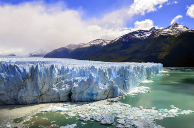 Lake with iceberg against cloudy sky