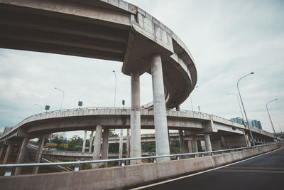 Bridges in city against cloudy sky